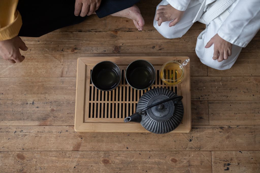 Overhead shot of a traditional tea ceremony featuring an iron teapot on a wooden tray.